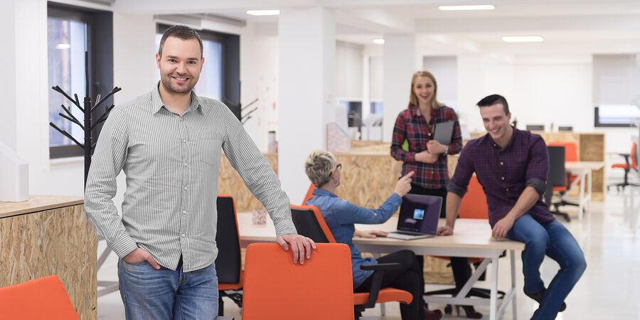 portrait of young businessman in casual clothes at modern  startup business office space,  team of people working together in background